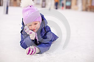 Adorable little girl laying on skating rink after