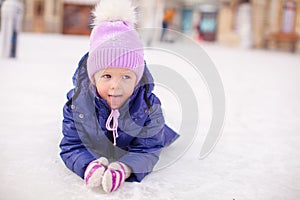 Adorable little girl laying on skating rink after