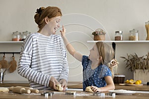 Adorable little girl leaving floury spot on mothers face