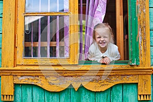 Adorable little girl looks out the window rural