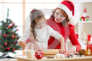 Adorable little girl and mother baking Christmas cookies