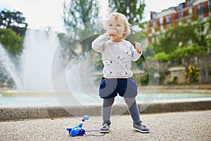 Adorable little girl outdoors in park eating bread