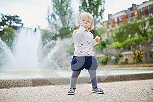 Adorable little girl outdoors in park eating bread