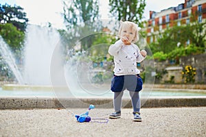 Adorable little girl outdoors in park eating bread