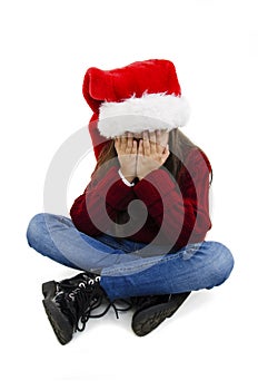 Adorable little girl over isolated background wearing christmas hat with sad expression covering face with hands while crying.