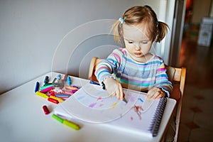 Adorable little girl painting with color pencils at home  in kindergaten or preschool