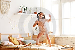 Adorable little girl in pajama preschool child holding hair brush as microphone and singing while standing on the bed