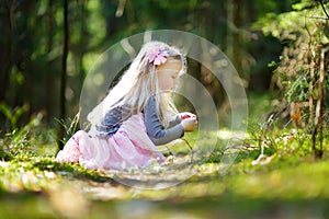 Adorable little girl picking the first flowers of spring in the woods on beautiful sunny spring day