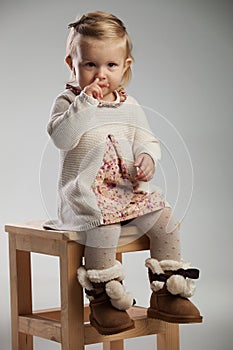 Adorable little girl picking her nose while sitting