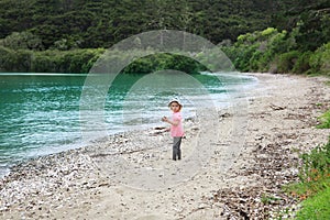 Adorable little girl in pink shirt on shelly Beach, NZ