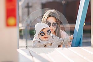 Adorable little girl play with her mom in the playground. Mom and daughter spend time together in Mother`s Day. Happy