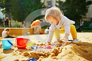 Adorable little girl on playground in sandpit