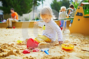 Adorable little girl on playground in sandpit