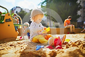 Adorable little girl on playground in sandpit