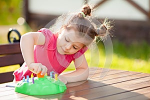 Adorable little girl playing board game outdoors