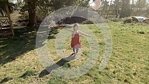 Adorable little girl playing with a broom in big backyard