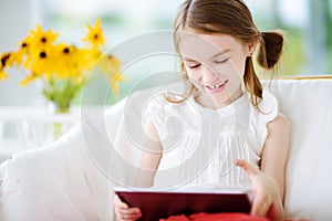Adorable little girl playing with a digital tablet