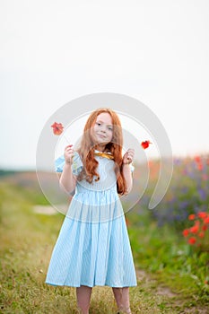 Adorable little girl playing on meadow with wildflowers