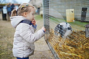 Adorable little girl playing with rabbits at farm