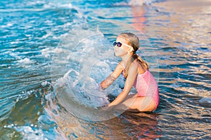 Adorable little girl playing in the sea on a beach photo