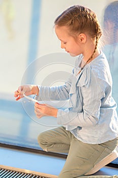 Adorable little girl playing with small model airplane in airport waiting for boarding