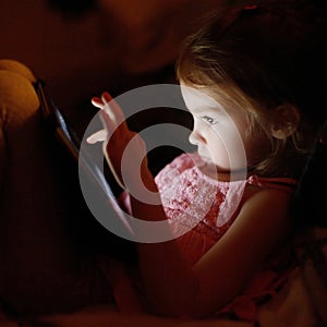 Adorable little girl playing on a tablet