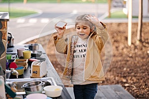 Adorable little girl playing in toy kitchen outdoors. Cute three year old girl have fun in kids city