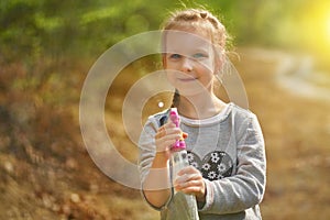 Adorable little girl playing with water gun on hot summer day. Cute child having fun with water outdoors. Funny summer