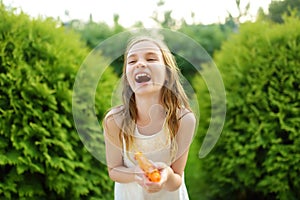 Adorable little girl playing with water gun on hot summer day. Cute child having fun with water outdoors