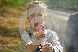 Adorable little girl playing with water gun on hot summer day. Cute child having fun with water outdoors. Funny summer