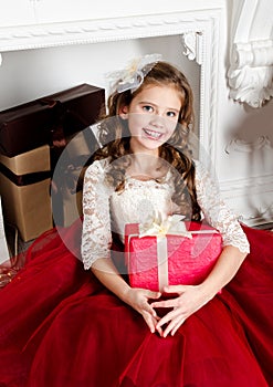 Adorable little girl in princess dress with gift box near firep
