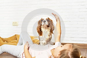 Adorable little girl with puppy playing at home. Child with little dog indoor. The best and friendliest pet for kids and
