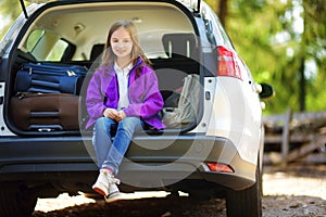 Adorable little girl ready to go on vacations with her parents. Kid relaxing in a car before a road trip.