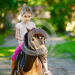 Adorable little girl riding a pony