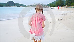 Adorable little girl running on the beach. Happy kid enjoy summer vacation. Slow Motion