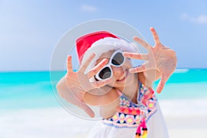 Adorable little girl in Santa hat during Christmas beach vacation