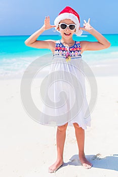 Adorable little girl in Santa hat during Christmas beach vacation