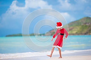 Adorable little girl in Santa hat on tropical beach