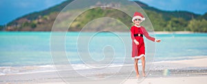 Adorable little girl in Santa hat on tropical beach