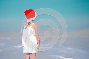 Adorable little girl in Santa hat on tropical beach