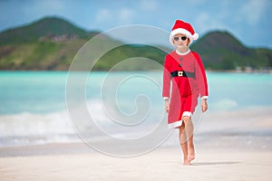 Adorable little girl in Santa hat on tropical beach