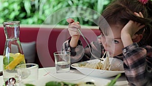 Adorable little girl savoring cheesy spaghetti in a cozy cafe