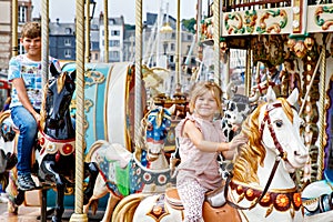 Adorable little girl and school kid boy having a ride on the old vintage merry-go-round in city of Honfleur France