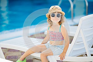 Adorable little girl sitting near the swimming pool