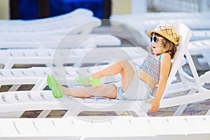 Adorable little girl sitting near the swimming pool