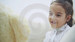 Adorable little girl sitting on the sofa, talking with her teddy.