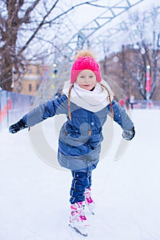 Adorable little girl skating on the ice-rink