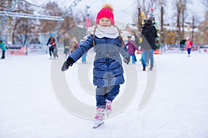 Adorable little girl skating on the ice-rink