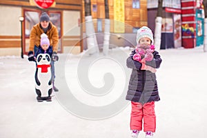 Adorable little girl on skating rink with father