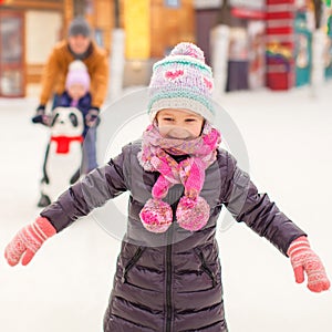 Adorable little girl on skating rink with father